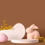 Decorative podiums with Easter egg, toy bunny and mimosa flowers on brown background