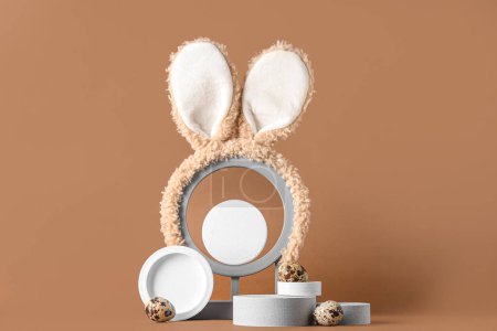 Podios decorativos con huevos de Pascua y orejas de conejo sobre fondo marrón