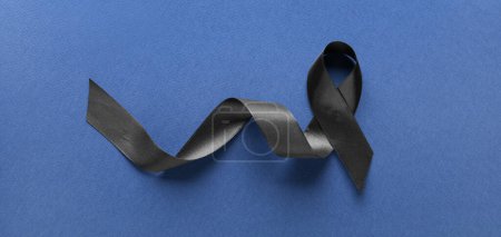 Black funeral ribbon on blue background, top view
