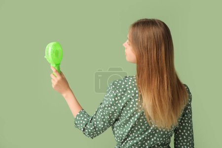 Téléchargez les photos : Jeune femme avec mini ventilateur portable sur fond vert, vue arrière - en image libre de droit