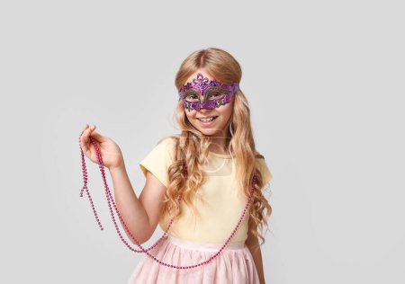 Photo for Cute little girl wearing carnival mask on light background - Royalty Free Image
