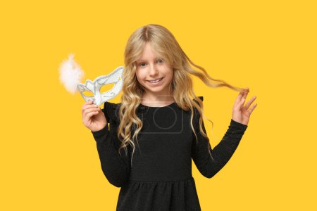 Photo for Funny little girl with carnival mask on yellow background - Royalty Free Image