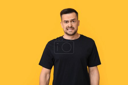 Photo for Handsome ashamed young man on yellow background - Royalty Free Image