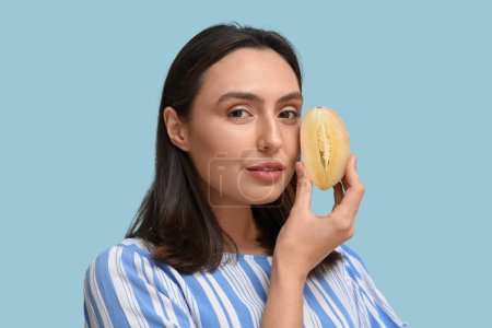 Photo for Beautiful young woman with chikoo fruit on blue background - Royalty Free Image