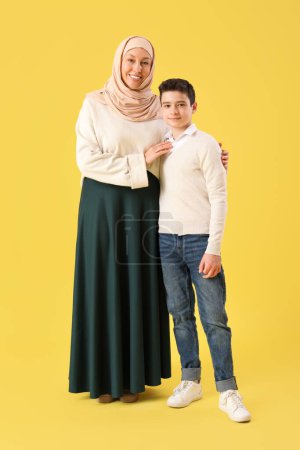 Feliz madre musulmana y su hijo sobre fondo amarillo. Celebración de Eid al-Fitr