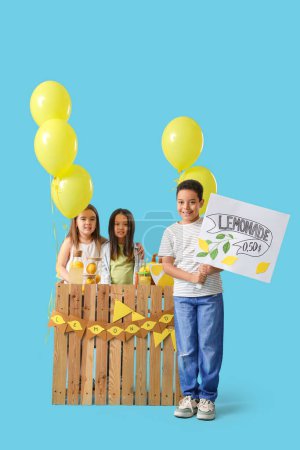 Cute little children at lemonade stand on blue background