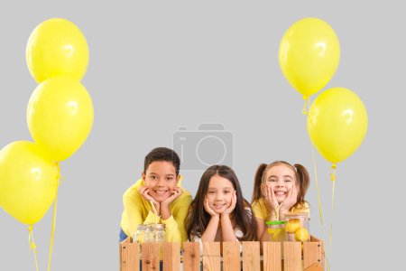 Cute little children at lemonade stand on light background