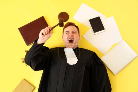 Male judge with gavel and items on yellow background, top view