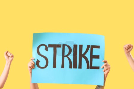 Photo for Protesting people holding placard with word STRIKE against yellow background - Royalty Free Image