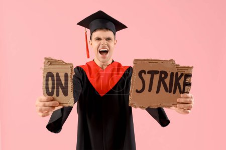 Protesting male graduate holding placard with text ON STRIKE against pink background