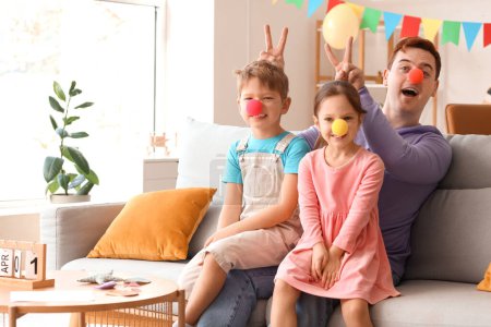 Father and his children with clown noses at home. April Fool's Day celebration