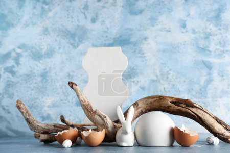 Photo for Decorative podiums with toy bunny, burning candles and tree branch on blue background - Royalty Free Image