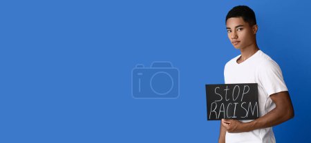 Foto de Adolescente afroamericano sosteniendo póster sobre fondo azul con espacio para texto. Detener el racismo - Imagen libre de derechos