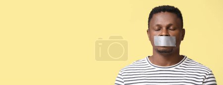 Foto de Hombre afroamericano con boca grabada sobre fondo amarillo con espacio para el texto. Detener el racismo - Imagen libre de derechos