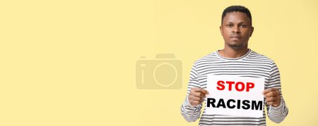Téléchargez les photos : Homme afro-américain tenant affiche sur fond jaune avec espace pour le texte. Arrêtez le racisme - en image libre de droit