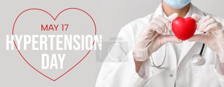 Doctor with red heart on light background. Banner for World Hypertension Day