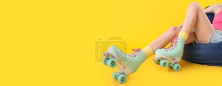 Legs of woman in roller skates on yellow background with space for text