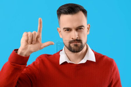 Photo for Handsome man showing loser gesture on blue background, closeup - Royalty Free Image