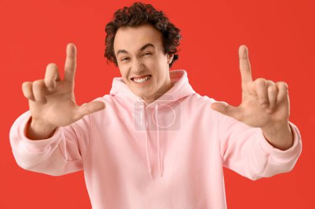 Young man showing loser gesture on red background, closeup