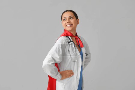 Belle femme médecin en costume de super-héros sur fond blanc