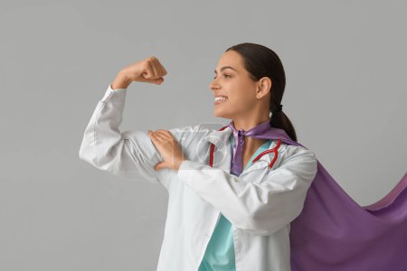Belle femme médecin en costume de super-héros montrant les muscles sur fond blanc