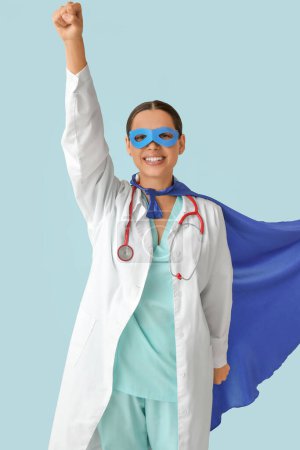 Belle femme médecin habillé en super héros sur fond bleu