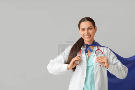 Beautiful female doctor in superhero costume on white background