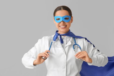 Jeune femme médecin en costume de super-héros sur fond blanc