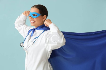 Belle femme médecin en costume de super-héros montrant les muscles sur fond bleu
