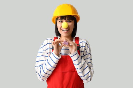 Foto de Joven constructora sonriente con sombrero de señora y soplador de fiesta sobre fondo blanco. Día del Loco - Imagen libre de derechos