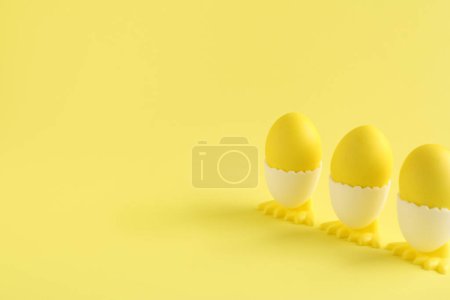 Easter eggs in holders on yellow background