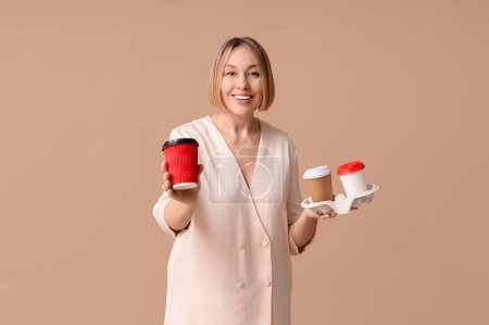Téléchargez les photos : Heureuse femme adulte avec des tasses en papier de café sur fond beige - en image libre de droit