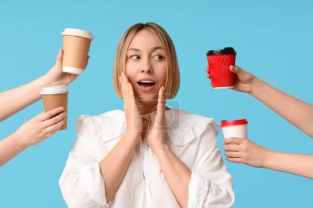 Téléchargez les photos : Femme adulte surprise et les mains féminines avec des tasses en papier de café sur fond bleu - en image libre de droit