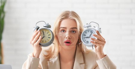 Photo for Stressed businesswoman with alarm clocks trying to meet deadline in office. Time management concept - Royalty Free Image