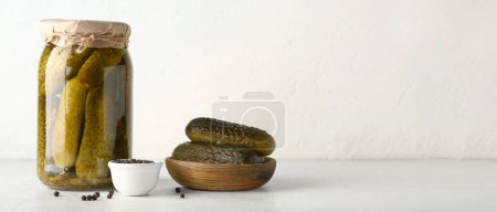 Téléchargez les photos : Bol et pot de concombres marinés savoureux avec du maïs poivré sur fond blanc avec de l'espace pour le texte - en image libre de droit