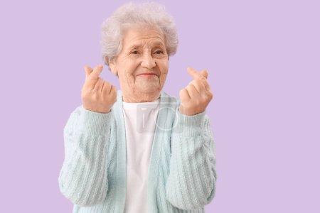 Femme âgée faisant c?ur avec ses doigts sur fond lilas