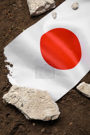 Japanische Flagge mit Steinschutt auf dem Boden. Erdbebenkonzept