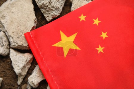 Chinesische Flagge mit Steinschutt auf dem Boden. Erdbebenkonzept