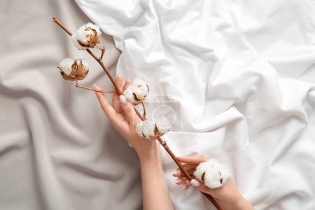 Female hands with cotton sprig on color bed sheets
