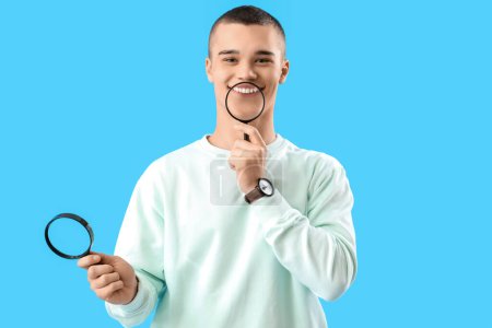 Young man with magnifiers  on blue background