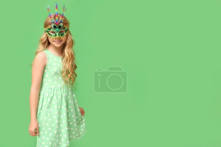 Photo for Adorable little girl wearing carnival mask on green background - Royalty Free Image