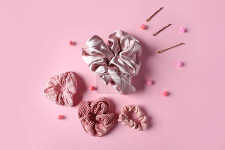 Scrunchies with hairpins and accessories for braids on pink background