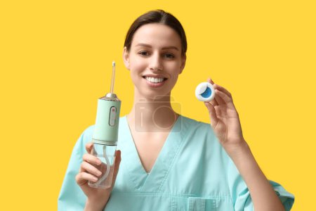 Zahnärztin mit Mundspülmaschine und Zahnseide auf gelbem Hintergrund