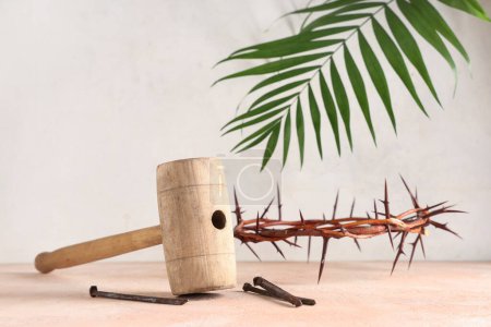 Photo for Crown of thorns with wooden hammer, nails and palm leaf on beige grunge table against white background. Good Friday concept - Royalty Free Image