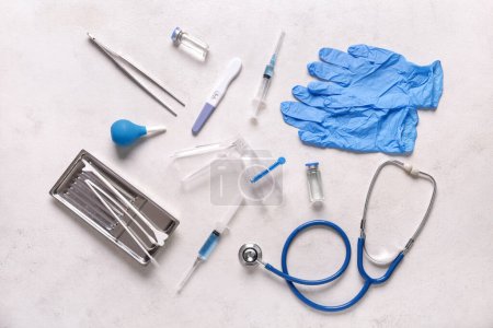 Stethoskop mit gynäkologischem Spekulum, Pap-Abstrichwerkzeugen und Schwangerschaftstest auf weißem Grunge-Hintergrund