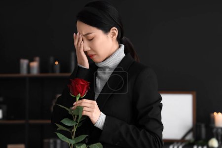 Luto joven mujer asiática con rosa en el funeral