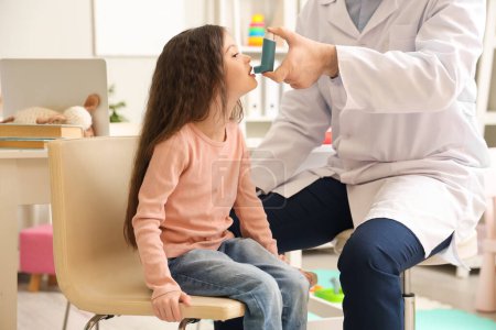 Little girl with doctor using inhaler in clinic