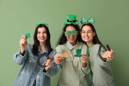 Schöne junge Frauen mit Hufeisen und Dekorationen auf grünem Hintergrund. St. Patrick 's Day Feier