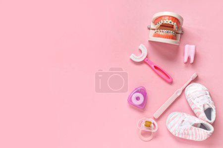 Téléchargez les photos : Brosses à dents pour enfants avec modèle à mâchoires, chaussures et sucette sur fond rose - en image libre de droit