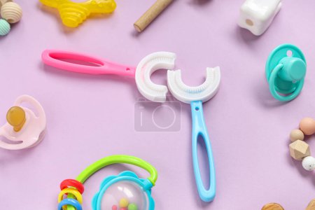 Téléchargez les photos : Brosses à dents pour enfants avec sucette et jouets sur fond lilas - en image libre de droit